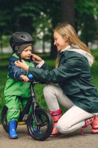 Mutter setzt ihrem Kind einen Fahrradhelm auf